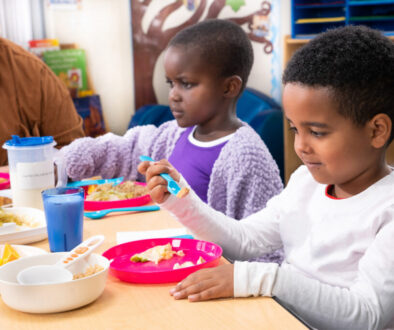A young child exploring food at a family-style meal