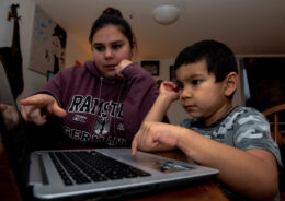 Parent and school-age child reviewing homework together on a laptop