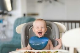 A baby lies calmly in a small bath, illustrating a gentle, supervised bath-time routine.