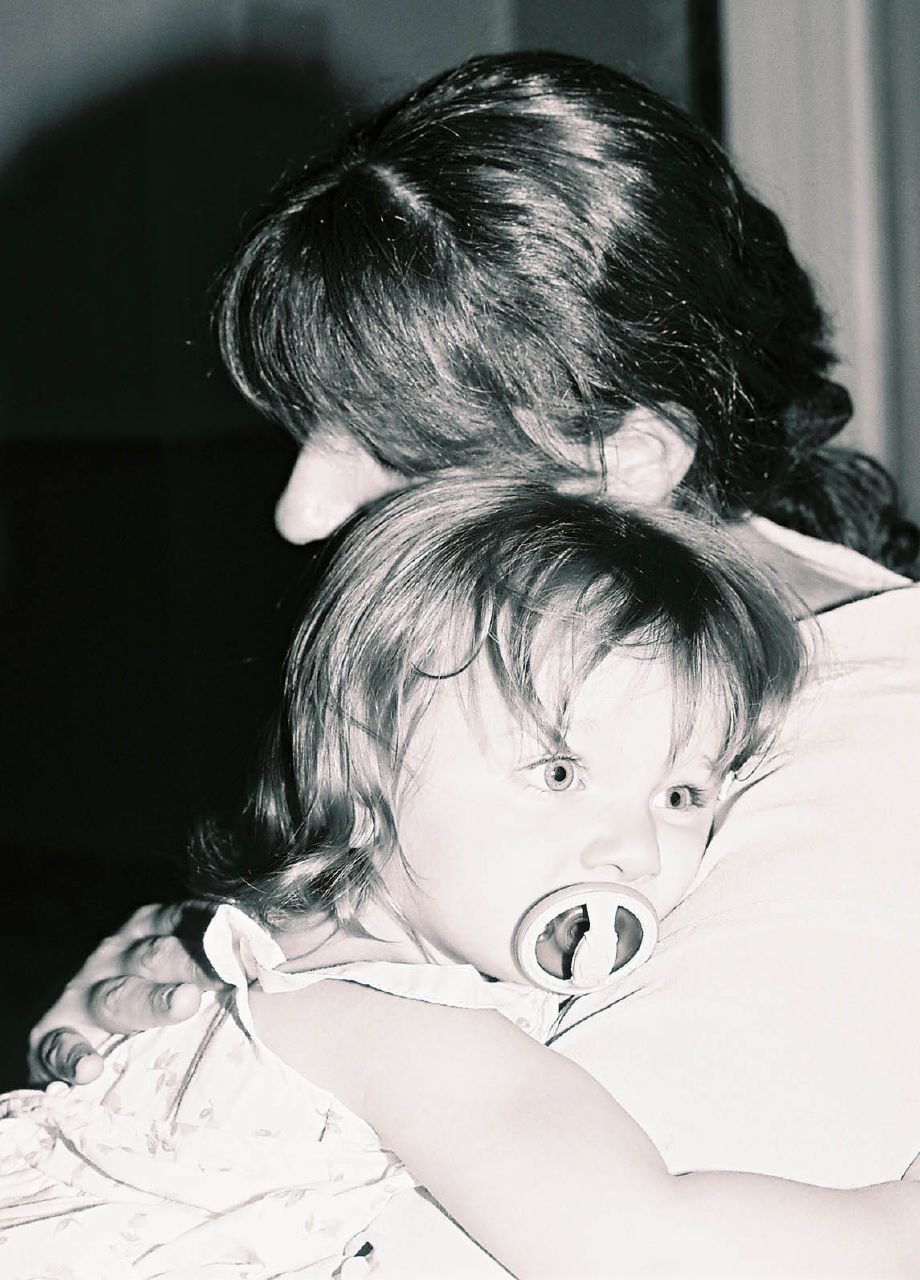 A caregiver holding a young child, used to illustrate a prepared babysitter handoff.
