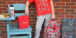 School-age child carrying a backpack outdoors.