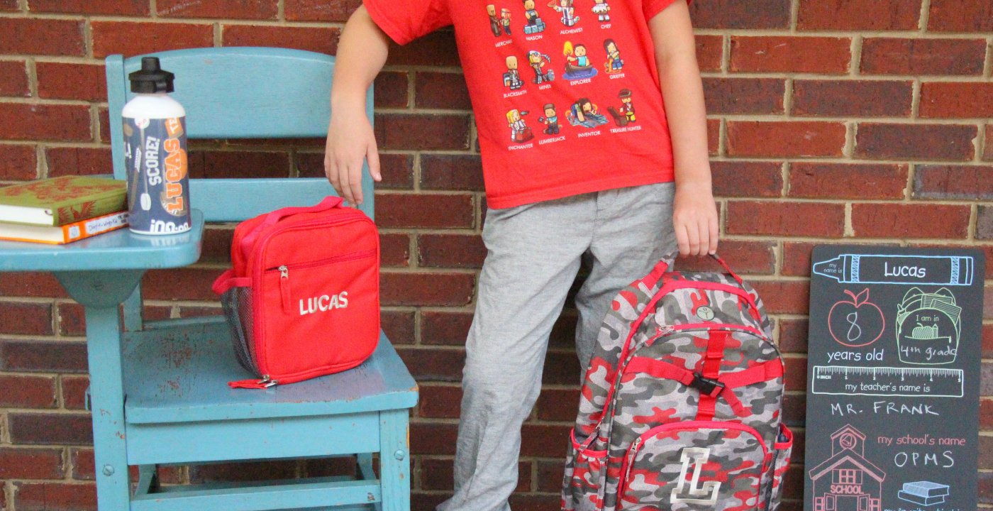 School-age child carrying a backpack outdoors.