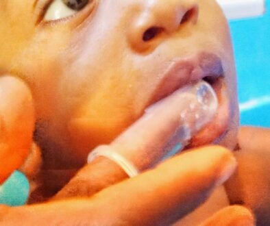 An adult gently brushes a baby’s mouth with a soft silicone finger brush.