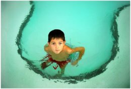 A child in a swimming pool, used as an editorial illustration for a guide about ear pain after swimming.