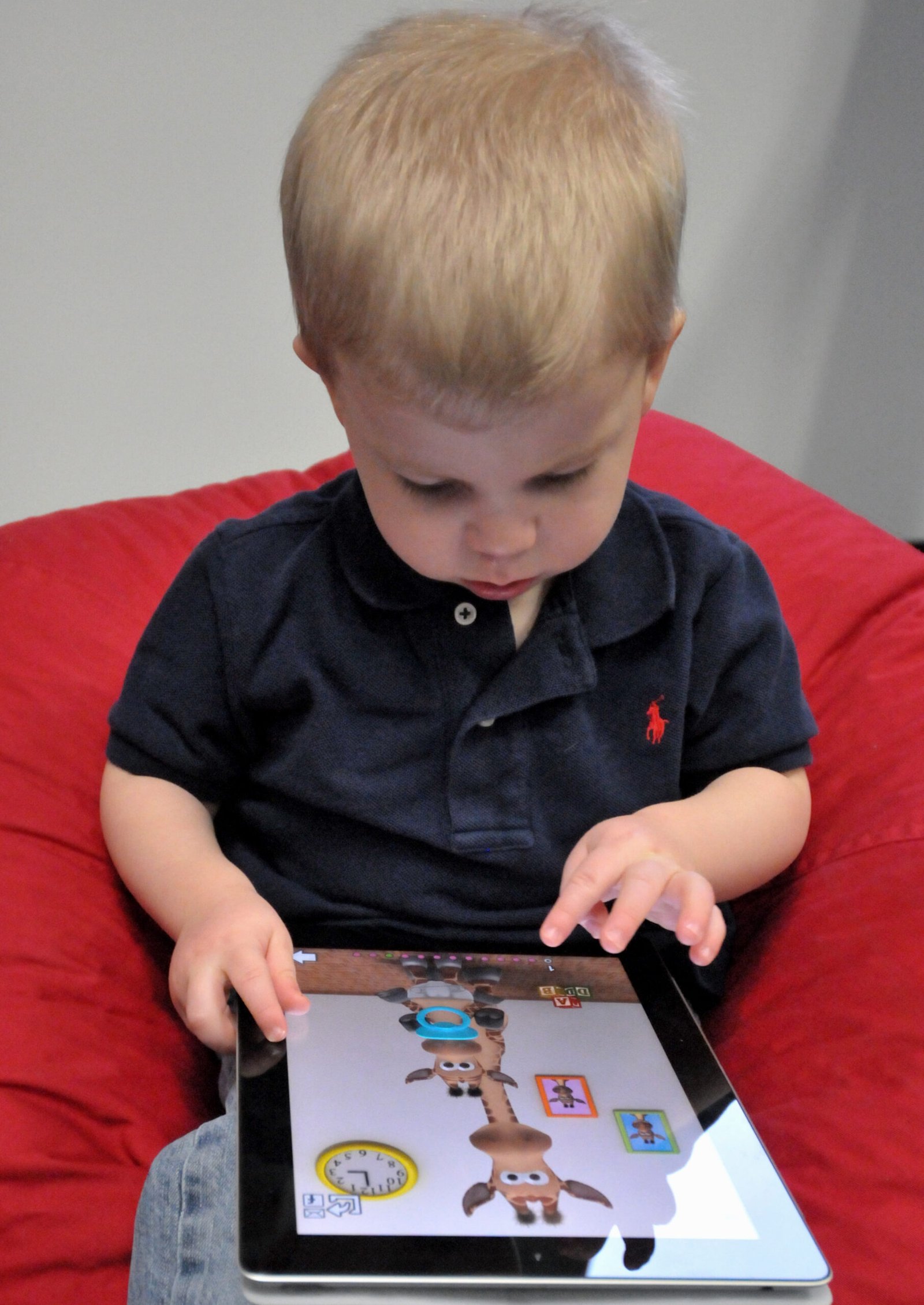 Young child using a tablet while an adult is nearby
