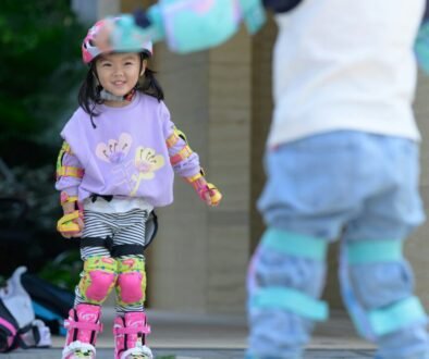 Two children rollerblading outdoors while wearing protective sports gear.