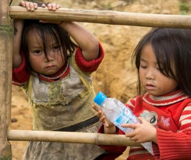 Two children look at a water bottle outdoors, illustrating a school-day bottle choice.