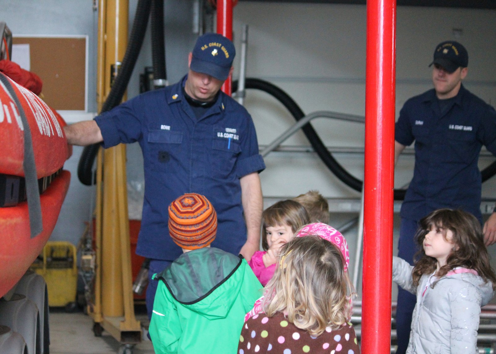 Children visiting a U.S. Coast Guard station where they learned about wearing life jackets near boats and water.