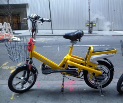 Yellow electric bicycle parked on a city street.