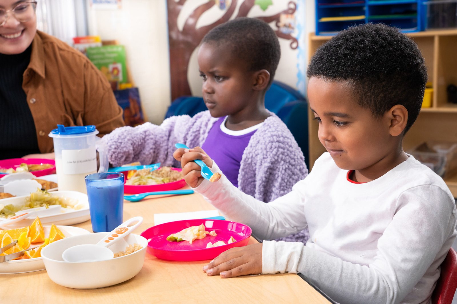 A family shares food at a table, illustrating a parent guide to starting solids and introducing allergenic foods safely.