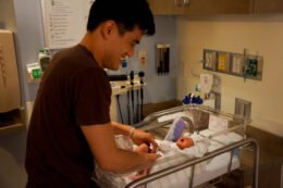 A father gently cares for a newborn, used as an editorial illustration for a parent guide about helping a baby through brief separations.