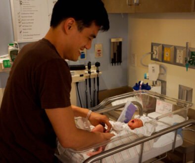 A father gently cares for a newborn, used as an editorial illustration for a parent guide about helping a baby through brief separations.