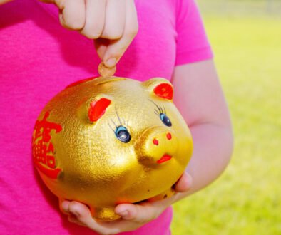 A child placing money into a piggy bank, used as an editorial illustration for a family money-skills guide.
