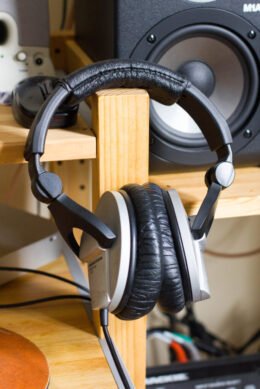 Over-ear headphones shown as an editorial illustration for a parent guide about volume-limiting headphones and a child’s school tablet.