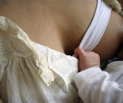 A mother breastfeeds a baby while wearing a nursing bra.
