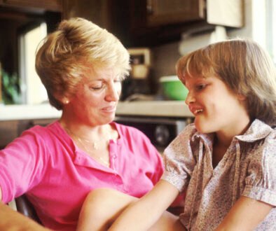 A mother and young daughter talk together in a close, calm conversation.