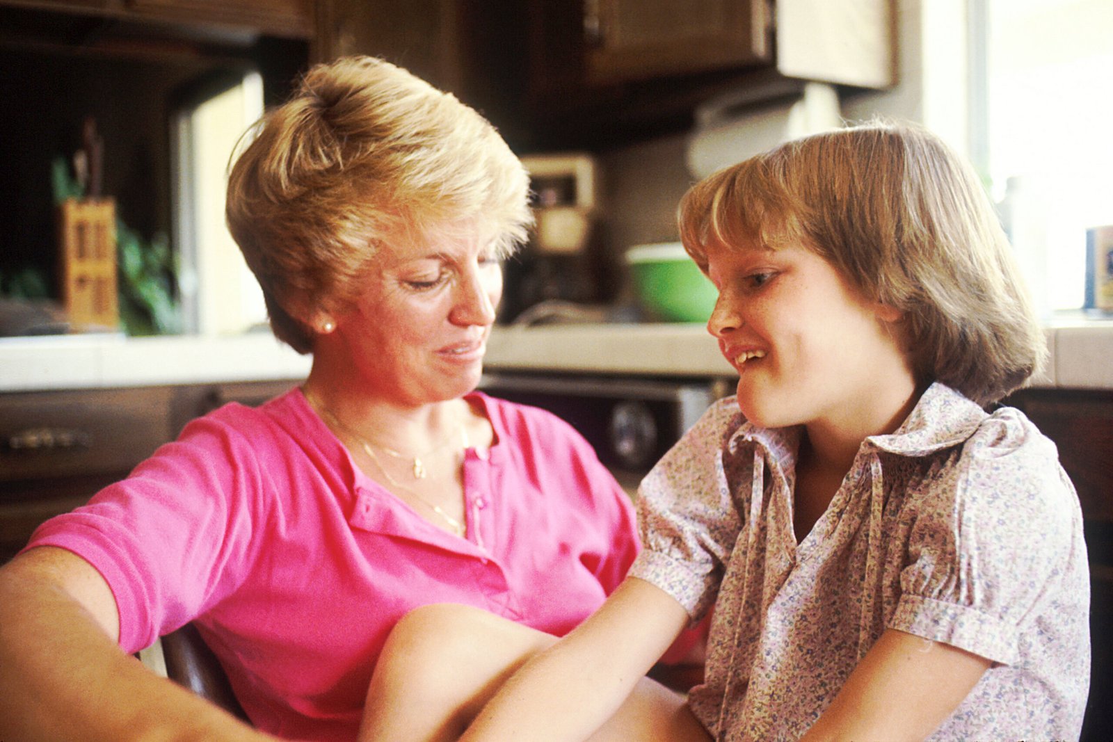 A mother and young daughter talk together in a close, calm conversation.