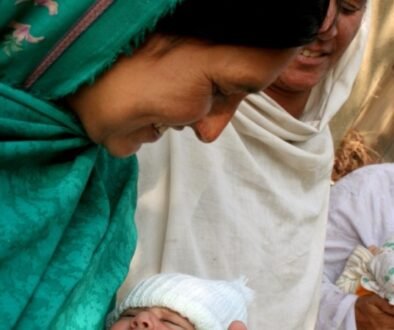 A mother gently holds her newborn baby close during a calm daytime moment.
