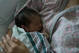 A newborn sleeping peacefully on a parent, illustrating the close comfort many families use while learning about safe newborn sleep routines.