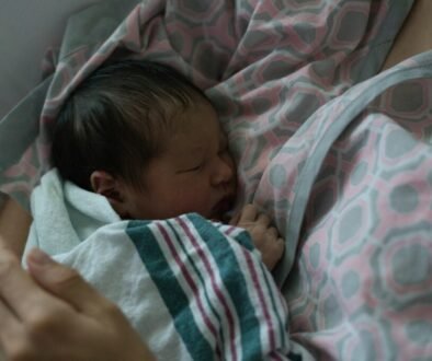 A newborn sleeping peacefully on a parent, illustrating the close comfort many families use while learning about safe newborn sleep routines.