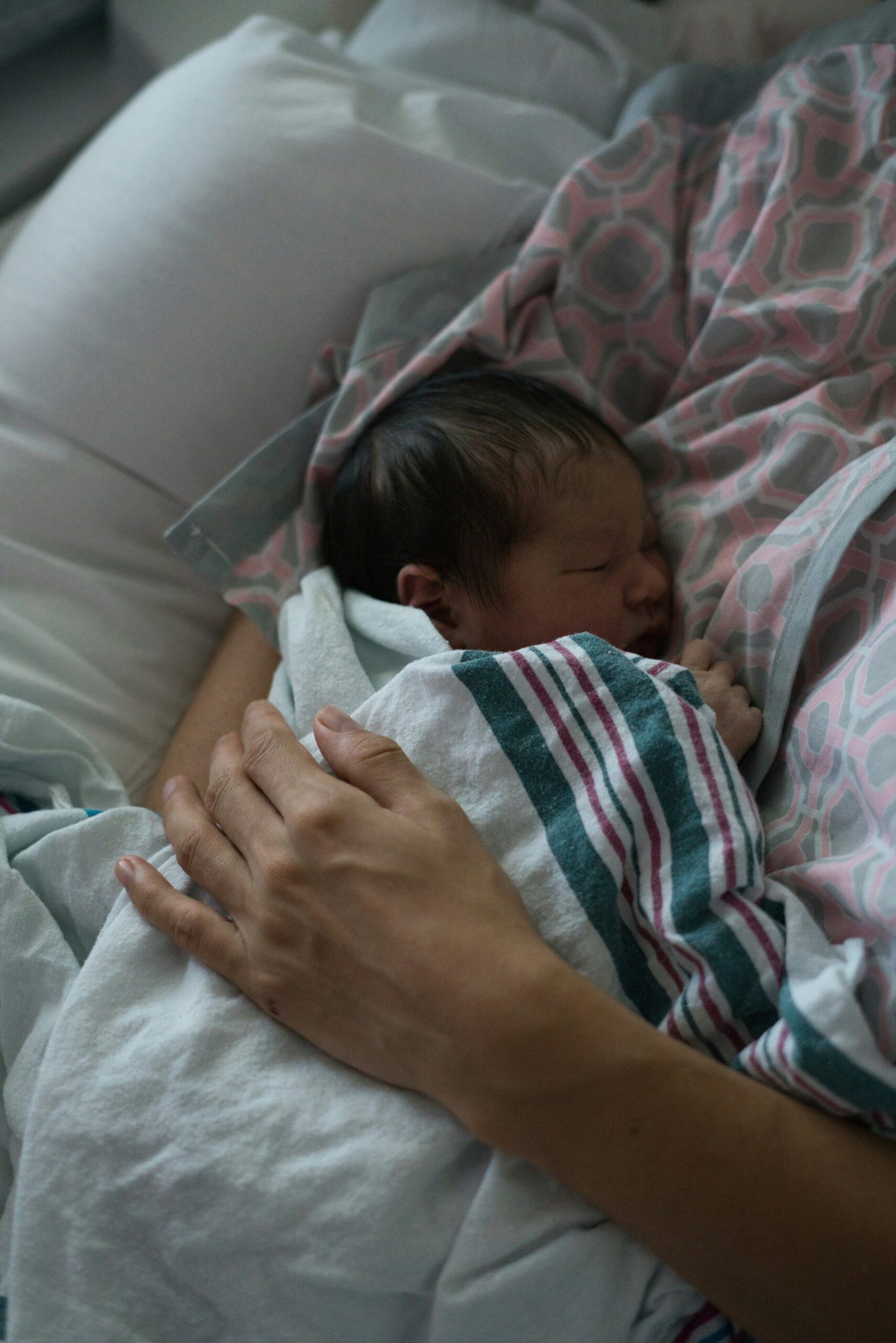 A newborn rests in a parent’s arms; editorial image for guidance about newborn grunts and straining during sleep.