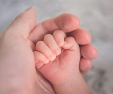 An adult gently holds a newborn’s hand, illustrating calm newborn umbilical cord stump care in the first weeks.
