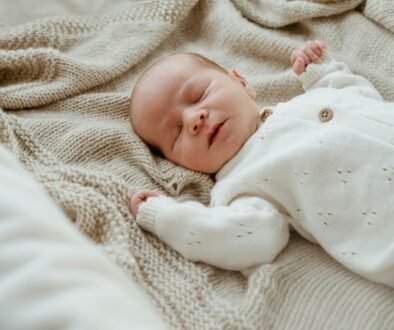 A newborn resting peacefully, used as an editorial illustration for a guide to choosing safe sleep layers.