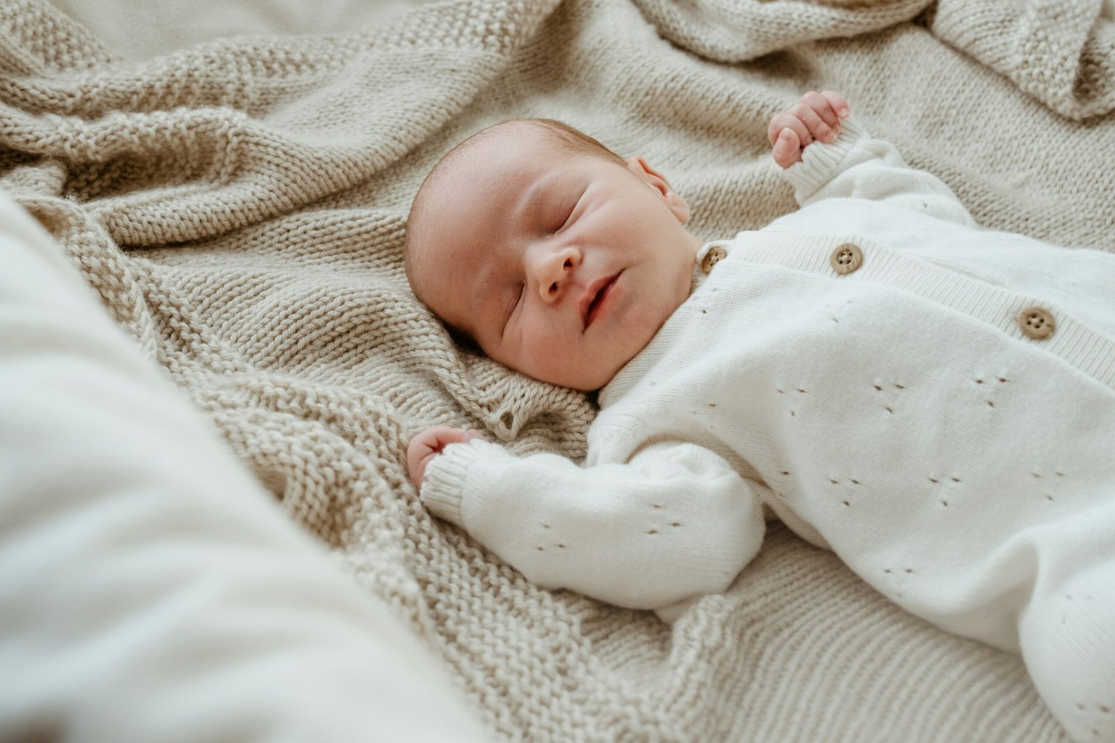 A newborn resting peacefully, used as an editorial illustration for a guide to choosing safe sleep layers.