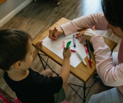An adult and young child color together at a table during a calm shared activity.
