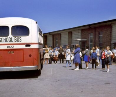 Children standing near a yellow school bus outside a school building