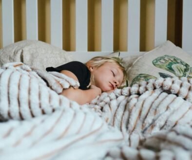 A child sleeping peacefully in bed under a blanket.