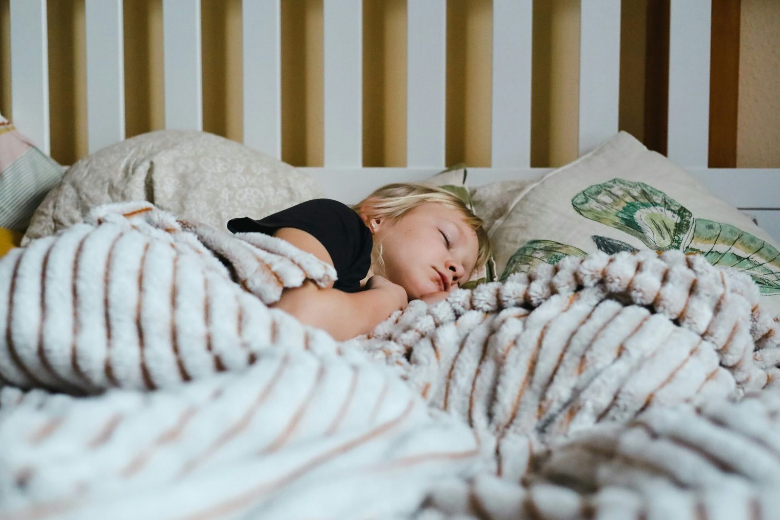 A child sleeping peacefully in bed under a blanket.