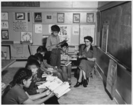 A teacher works with children in a classroom; a public-domain National Archives image used as an editorial illustration for classroom supports.