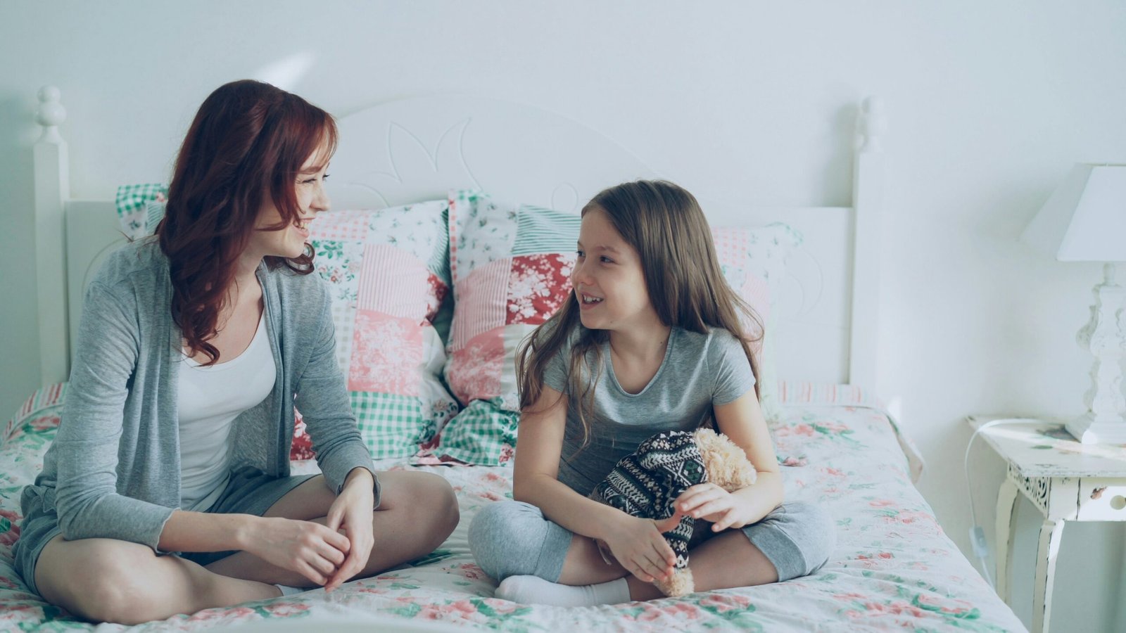 A parent and young child talk together at home, illustrating a calm body-safety conversation.
