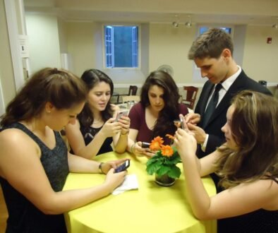 A small group of young people using smartphones, used as an editorial illustration for a parent guide to Discord age verification.