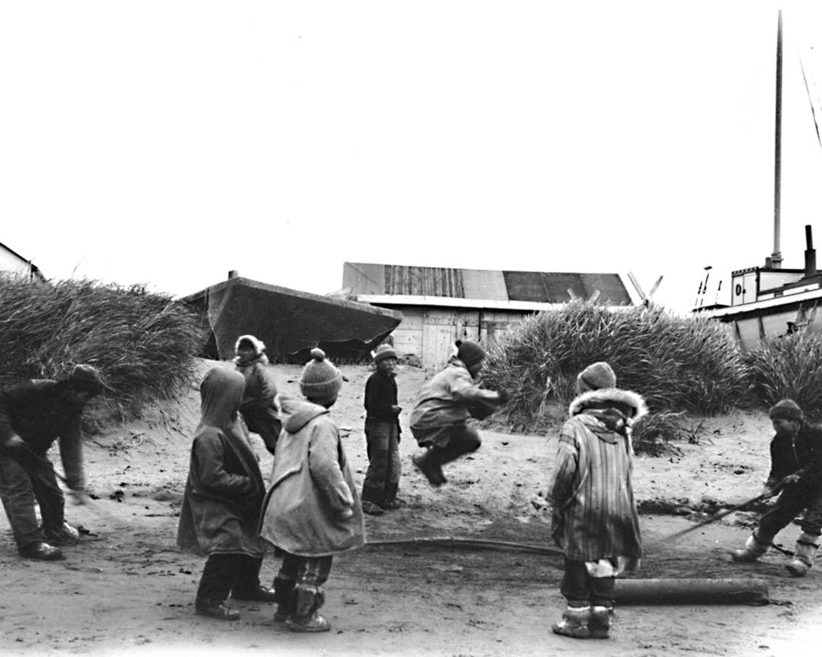 Children outdoors taking turns jumping rope during active play.