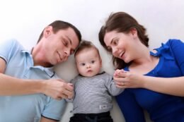 Two parents holding and looking at their baby at home.